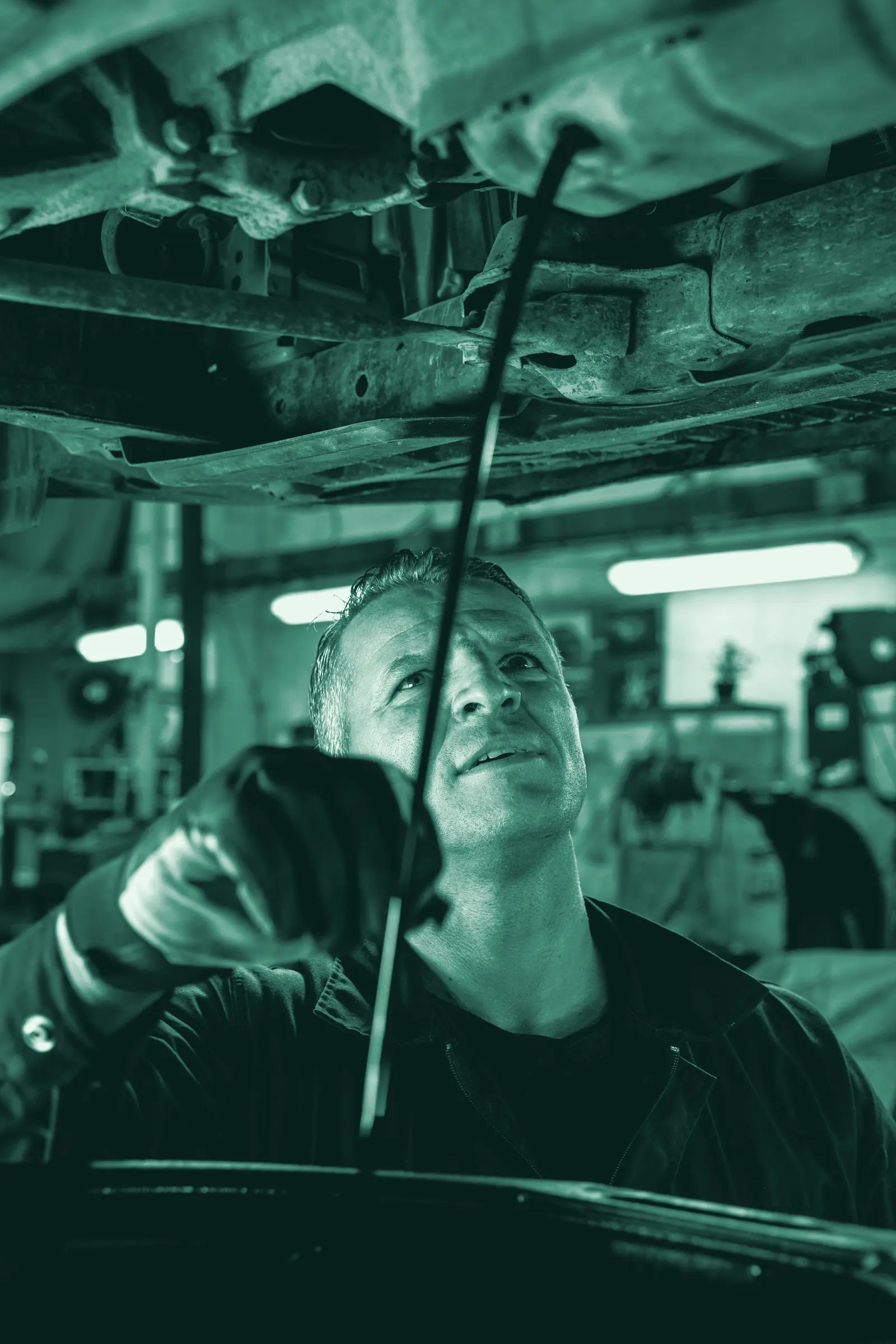 Illustrative photo: a mechanic working underneath a car on a lift.