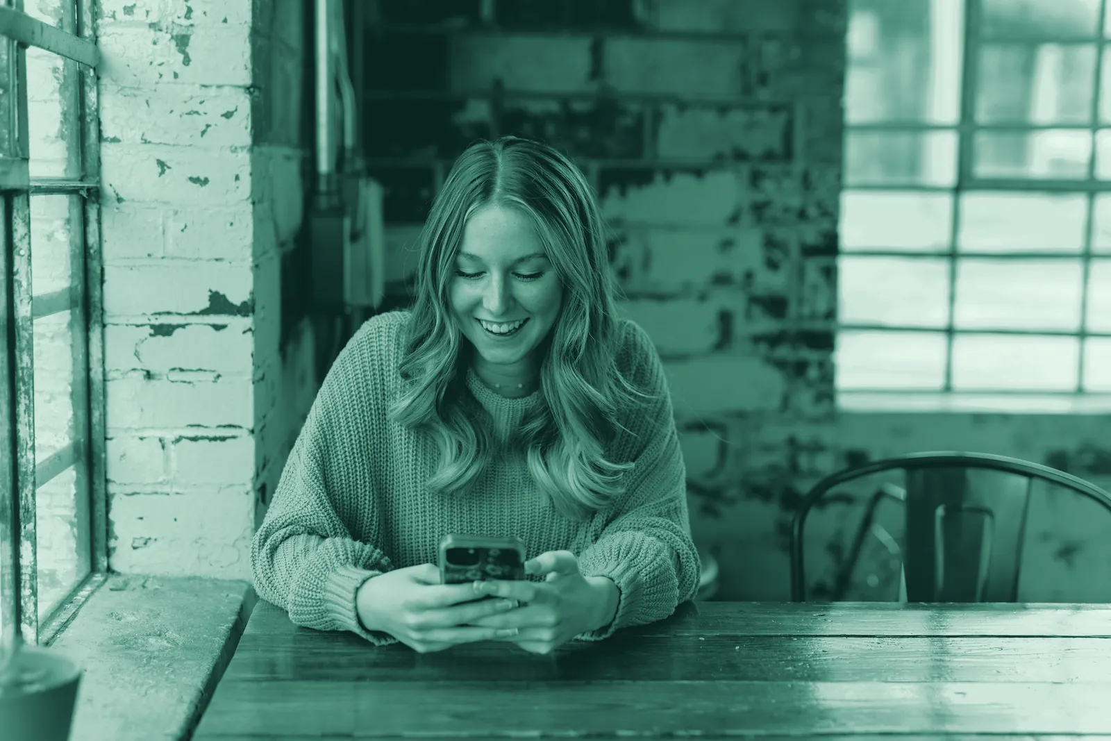 Illustrative photo: a woman smiling as she reads a message on her phone.