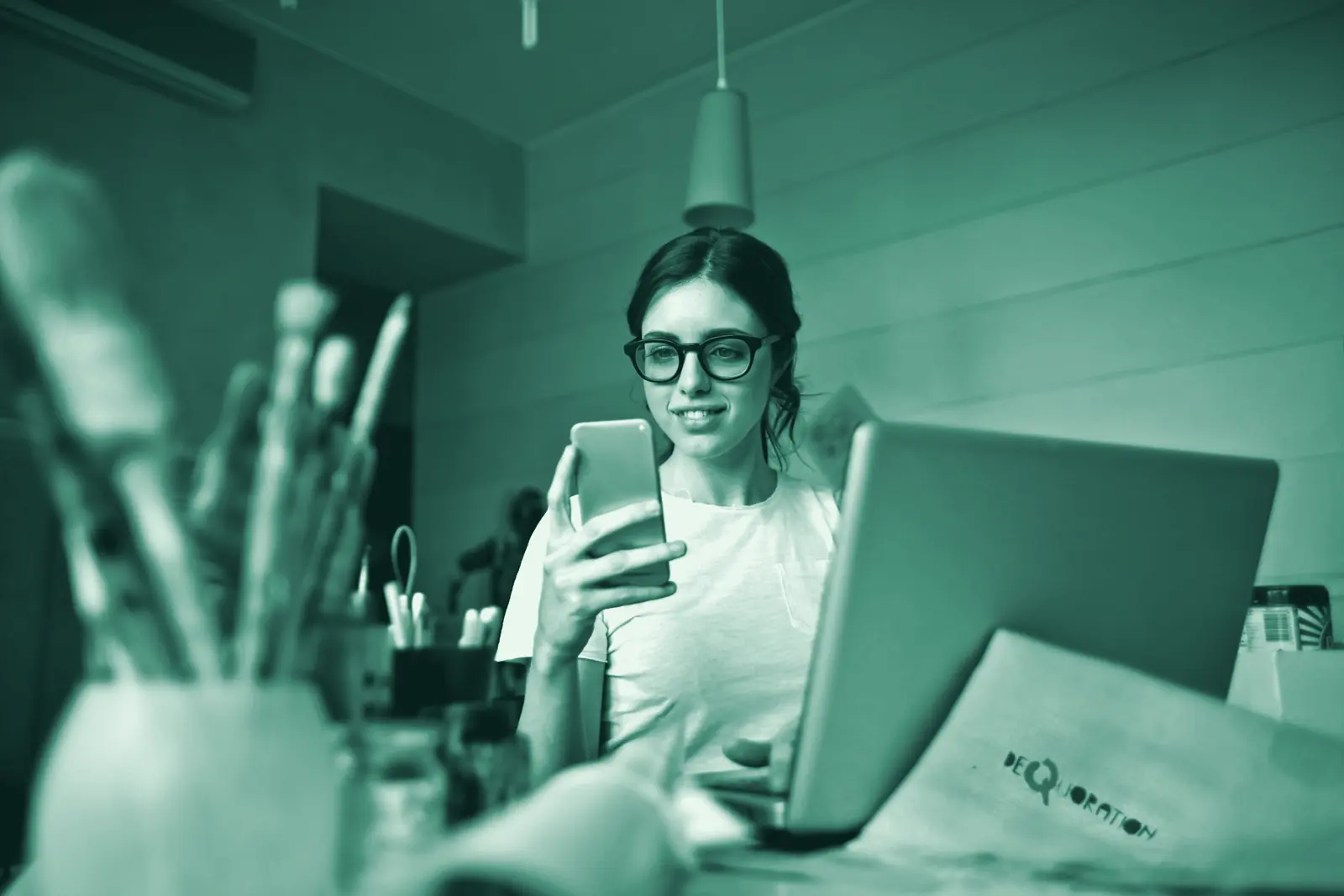 Illustrative photo: an owner working from her desk on phone and laptop.